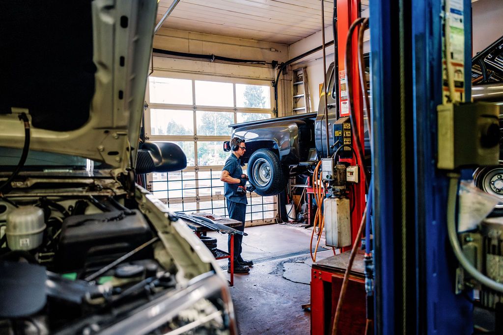 A technician under a lifted truck in the service bay