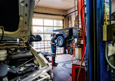 A technician under a lifted truck in the service bay