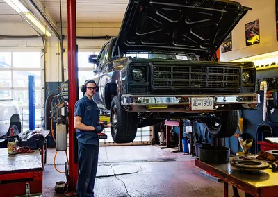 A pickup truck on a hoist in the service bay