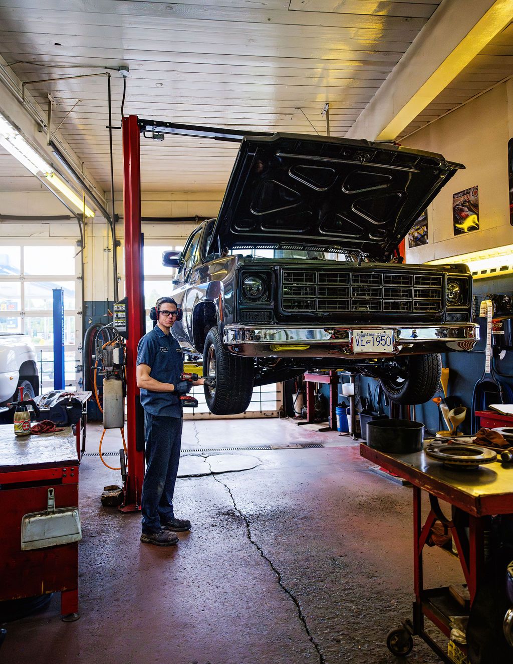 A pickup truck raised on a hoist in one of the service bays, showing its underside