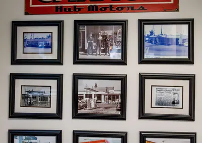 A wall of framed photos under a vintage Garage Hub Motors sign