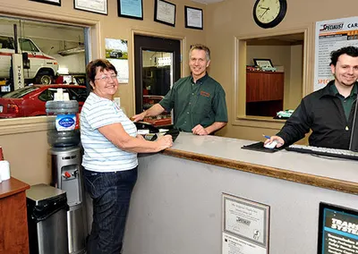 A customer at the front counter with two staff