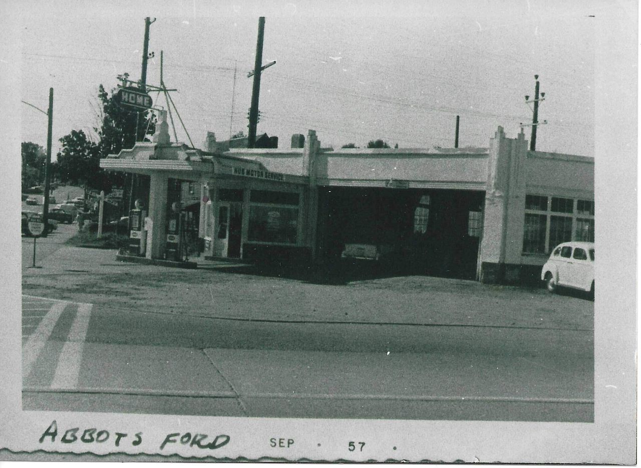 Hub Motor Service in September 1957, in black and white, with its gas pumps, a tall sign reading Home, and the Hub Motor Service sign over the door.