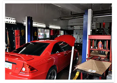 A red car with its hood up in the service bay