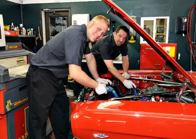 Two technicians working on a red car